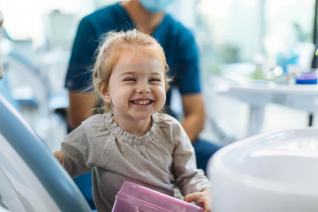 Criança a sorrir numa sala de dentista.