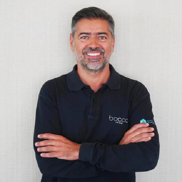 Dr. Jaime a sorrir, com os braços cruzados, t-shirt de manga comprida com o logo da Bocca clínica.